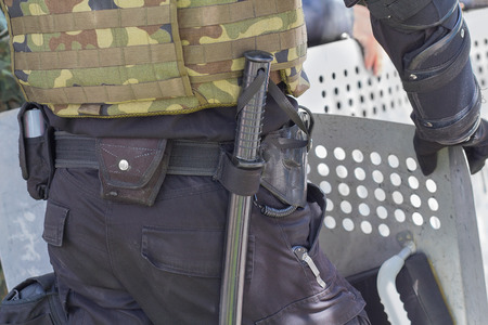 Baton and a shield of a policeman standing in a cordon
