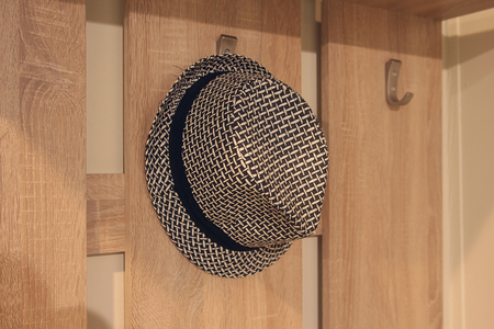 Stylish hat hanging on a hanger in the hallwayの写真素材