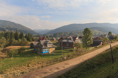 Village is illuminated by the sun and the mountains are far away. Carpathians, Ukraineの写真素材