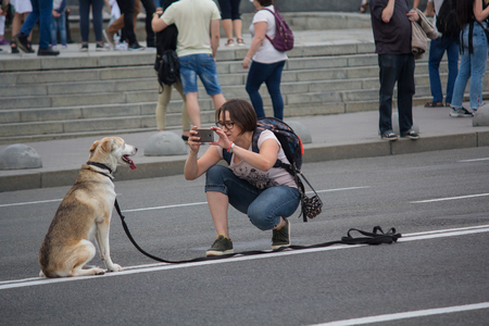 Kiev, Ukraine - July 09, 2017: Woman takes pictures of a mongrel dog on a road in the city centerのeditorial素材