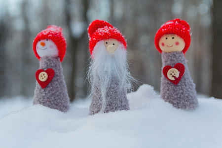 Three benevolent gnomes with hearts at the edge of a winter forestの写真素材