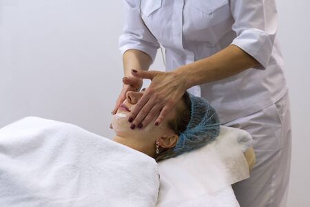 Woman getting face treatment with white nourishing creme in spa salon. Face massage. Spa skin and body careの写真素材
