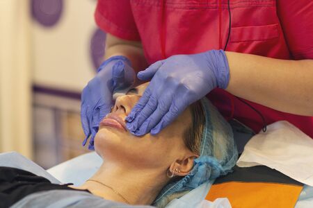 Facial skin cleansing in a cosmetology center. Woman on anti-aging procedure in a beauty salon