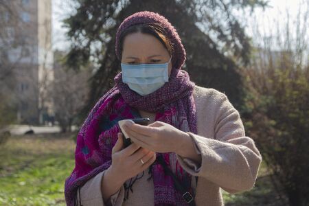 Serious woman in a protective mask with a smartphone. Peopleの写真素材