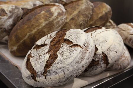 Batch of fresh baked buns and loafs on a market counter . Bread manufacture