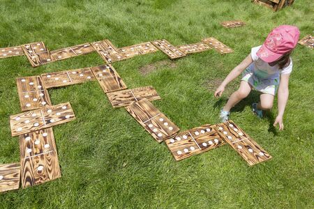 Girl playing in a large wooden dominoes laid out on the lawn. Gamesの写真素材