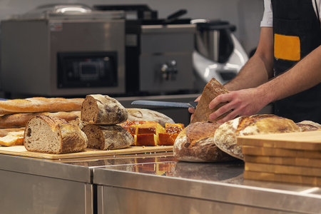 Baker in bakery cutting fresh bread. Foodの写真素材