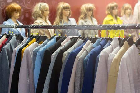 Multi-colored women's coats on hangers and mannequins in the store. Fashion and sale