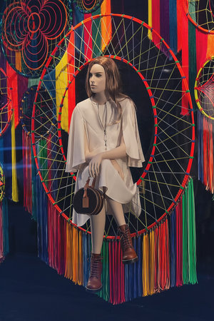 Female mannequin in an elegant dress and handbag in a fashion store window