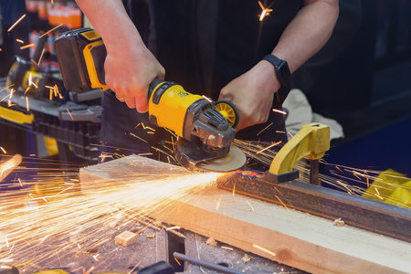 Craftsman using a grinder to cut metal in a workshop with sparks flying. Industryの写真素材