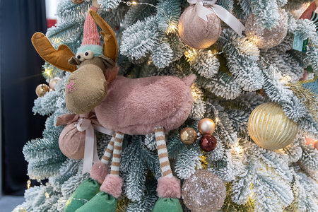 Christmas tree toy in the form of a funny reindeer and golden balls on snow-covered branches of the Christmas tree. Christmas background.の写真素材