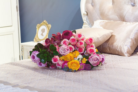 Beautiful bouquet of roses on the bed in an elegant bedroomの写真素材