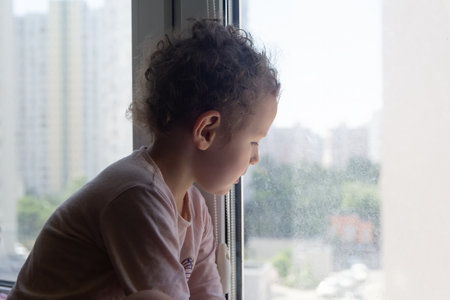 A sad child looks out the window. Peopleの写真素材