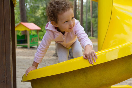 A sweet little child with curly hair on the playground. Peopleの写真素材
