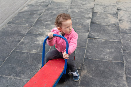 Pretty curly child rides on a swing-balancer. Peopleの写真素材