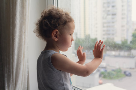 A sad child looks out the window. Peopleの写真素材