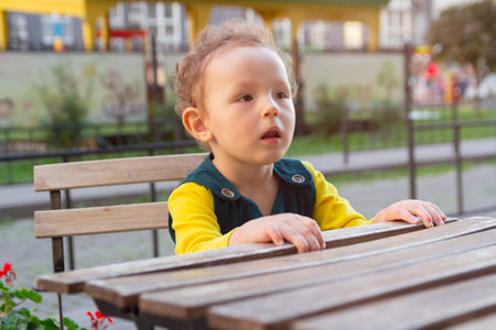 Curly girl sits at the table.の写真素材