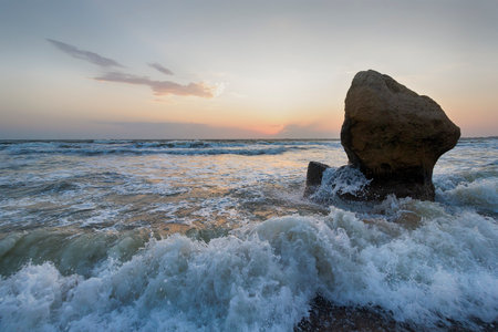Splashing waves beat against the rocks on the beach at sunset. Crimeaの写真素材