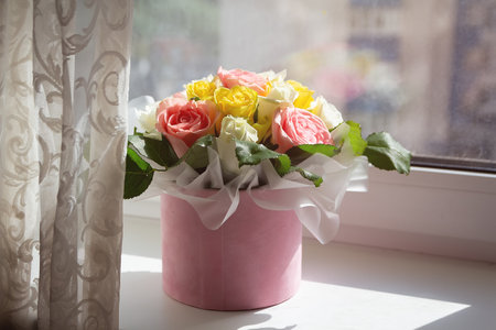 A beautiful bouquet of roses stands on the windowsill sunny day. Flowersの写真素材