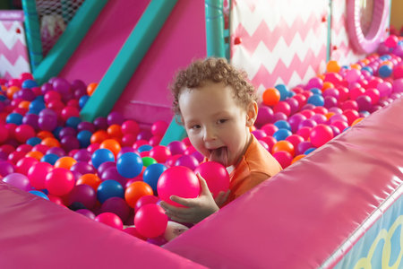 A happy baby plays in a multicolored ball pool in a children's playroom. Peopleの写真素材