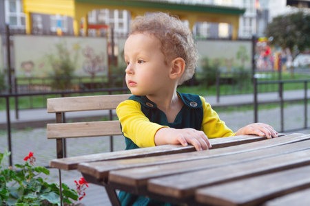Curly girl sits at the table of a street cafe.の写真素材