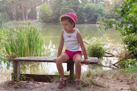 A child in panama hat sits on a bench on the lake. Peopleの写真素材