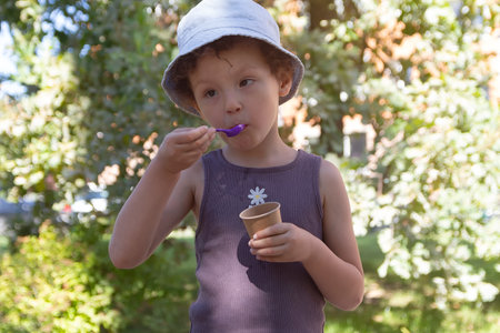 A child in a hat eats in the park.の写真素材