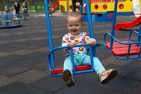 The baby rides on a swing on the playground in the park.の写真素材