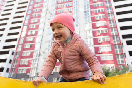 The child plays on the playground near a multi-storey building. Peopleの写真素材