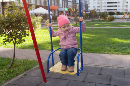 Cute baby on the swing on the playground near the house. Peopleの写真素材