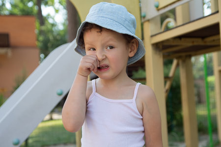A distressed child in a panama hat on the playground. Peopleの写真素材