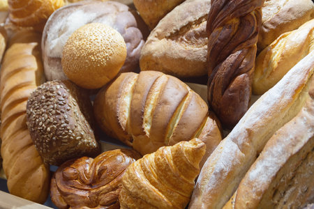 Assorted fresh bread varieties displayed artfully on a neutral background, showing textures. Food