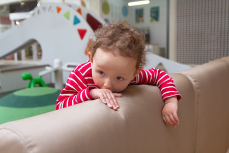 Pretty curly child plays a children's game room. Peopleの写真素材