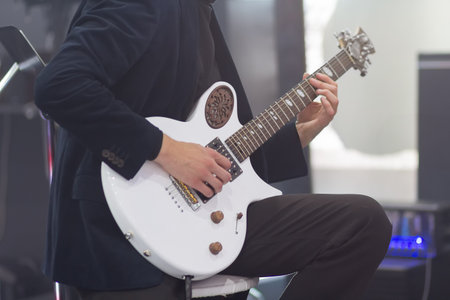 Man's hands playing on an electric guitar in a band on stage, entertainment of a guitarist artist...