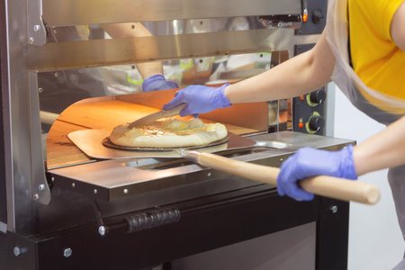 Female cook takes out pizzas from the oven. Foodの写真素材