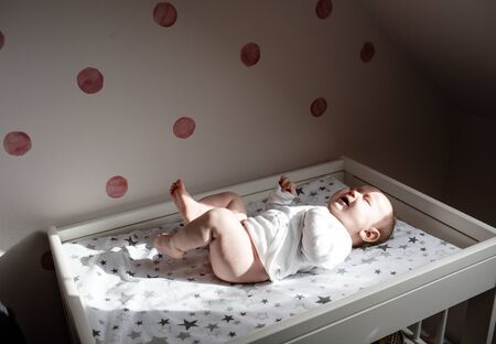 A newborn is screaming on a changing table. Stomach pain, childhood cramps. Crying newborn baby. The first year of life is restless.の写真素材
