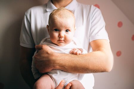 Portrait of a newborn baby. Father holds a child in her arms. The first year of life. Care and...