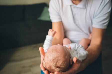 Portrait of a newborn baby. Father holds a child in her arms. The first year of life. Care and healthの写真素材