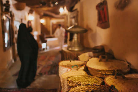 Middle East, old bazaar. There are spices on the counter. Blurry woman in black burqa and abaya on the background.のeditorial素材