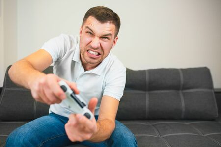 Young man sit in room during quarantine. Intense game and emotional guy using joystick or gamepad....