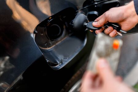 Man with credit card opening fuel tank of his new car. Cashless calculation of money. Fuel, oil...