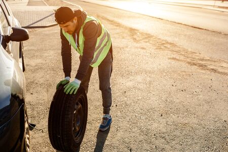 The driver should replace the old wheel with a spare. Man changing wheel after a car breakdown....