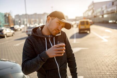 Man drinking coffee in the parking lot. Shopping mall. A man drinks coffee in the parking lot of a...