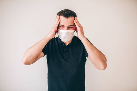 Young sick man isolated over background. Guy in black shirt suffer from headache. Hild hands on head. Sick ill person in studio alone.の写真素材