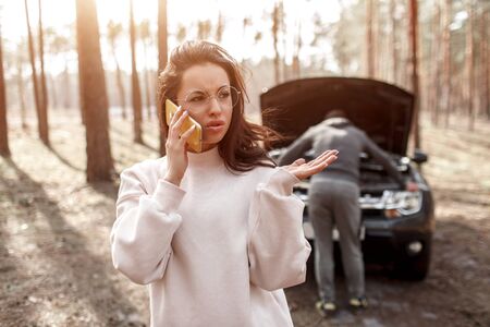 The car broke down. The guy is trying to fix the car. A young woman calls and asks for help in...