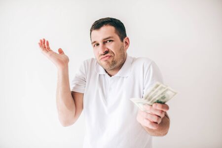 Young man isolated over white background. Guy wonder holding one hand a bit up. Bills money in...