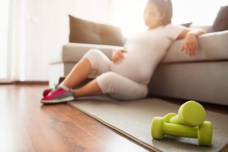 Close-up on a dumbbell. Pregnant woman with dumbbell. Active sporty life, wellness.の写真素材