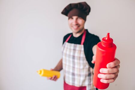 Young man isolated over background. Blurred defocused picture of guy holding red and yellow bottles...