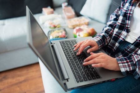 Food delivery concept. A young woman orders food using a laptop at home.の写真素材