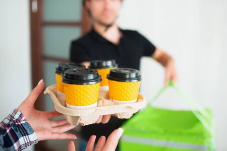 Food Delivery Man Brought Food Home To Young Woman. She wants to pay for the order using the applications in the smartphone.の写真素材
